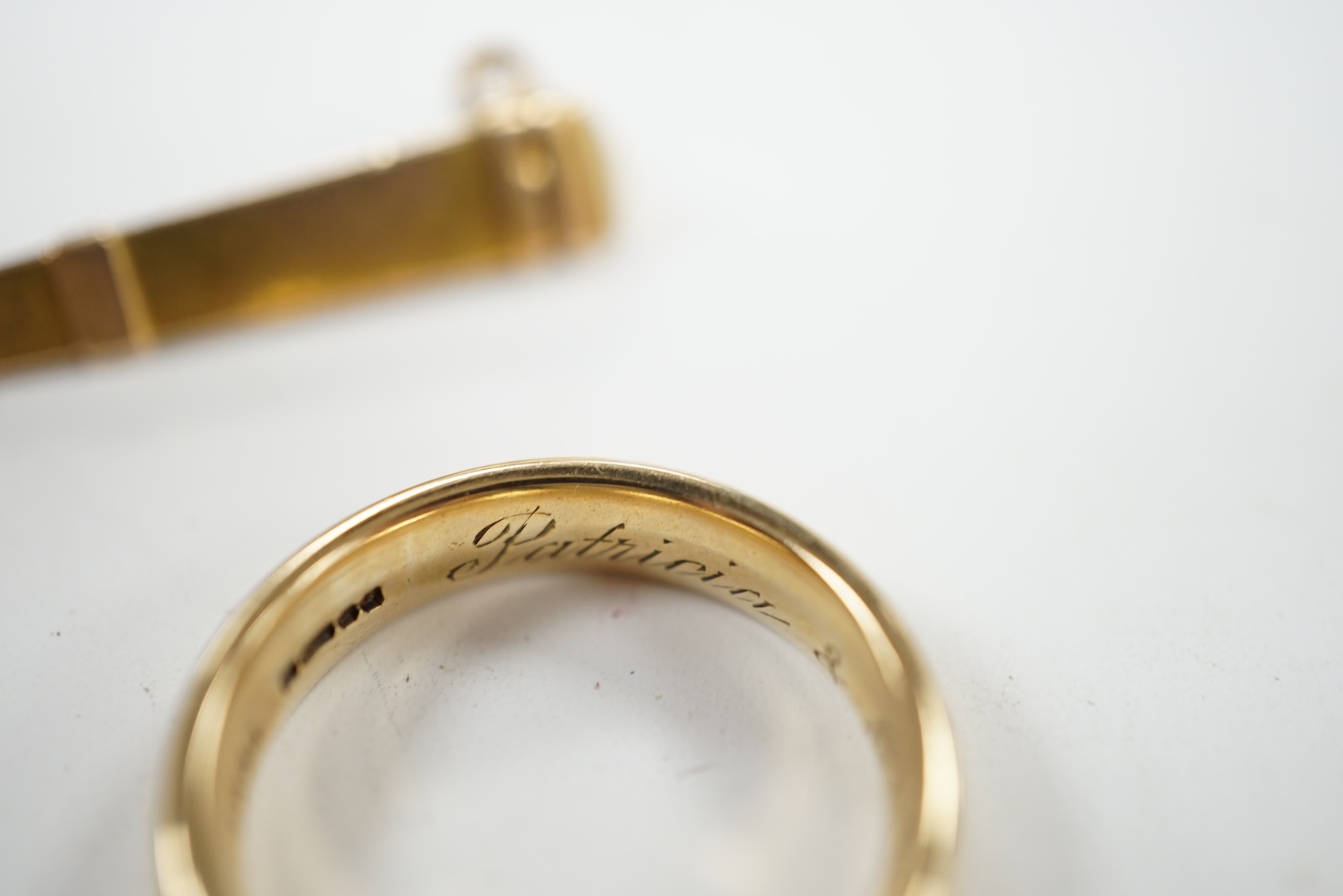 A 9ct gold wedding band, with engraved inscription, size Q and a yellow metal needle? case, 8.4 grams. Condition - fair